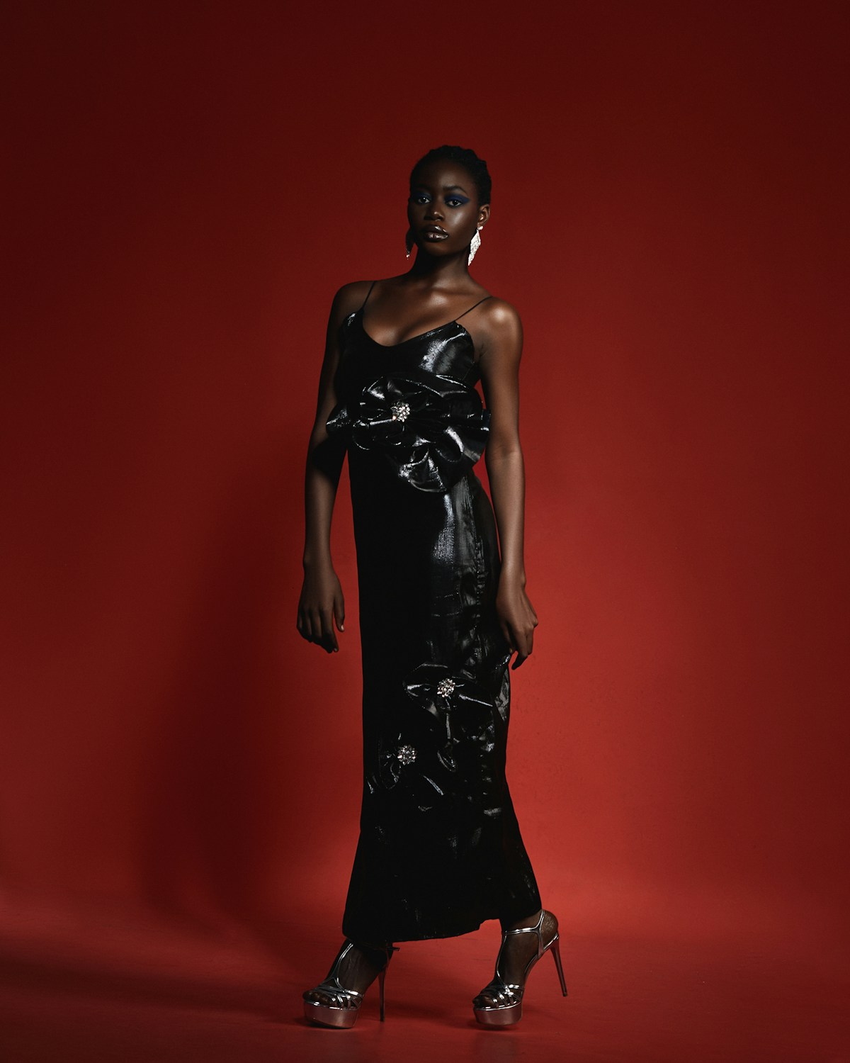 Model in a sculptural black evening gown against a red backdrop